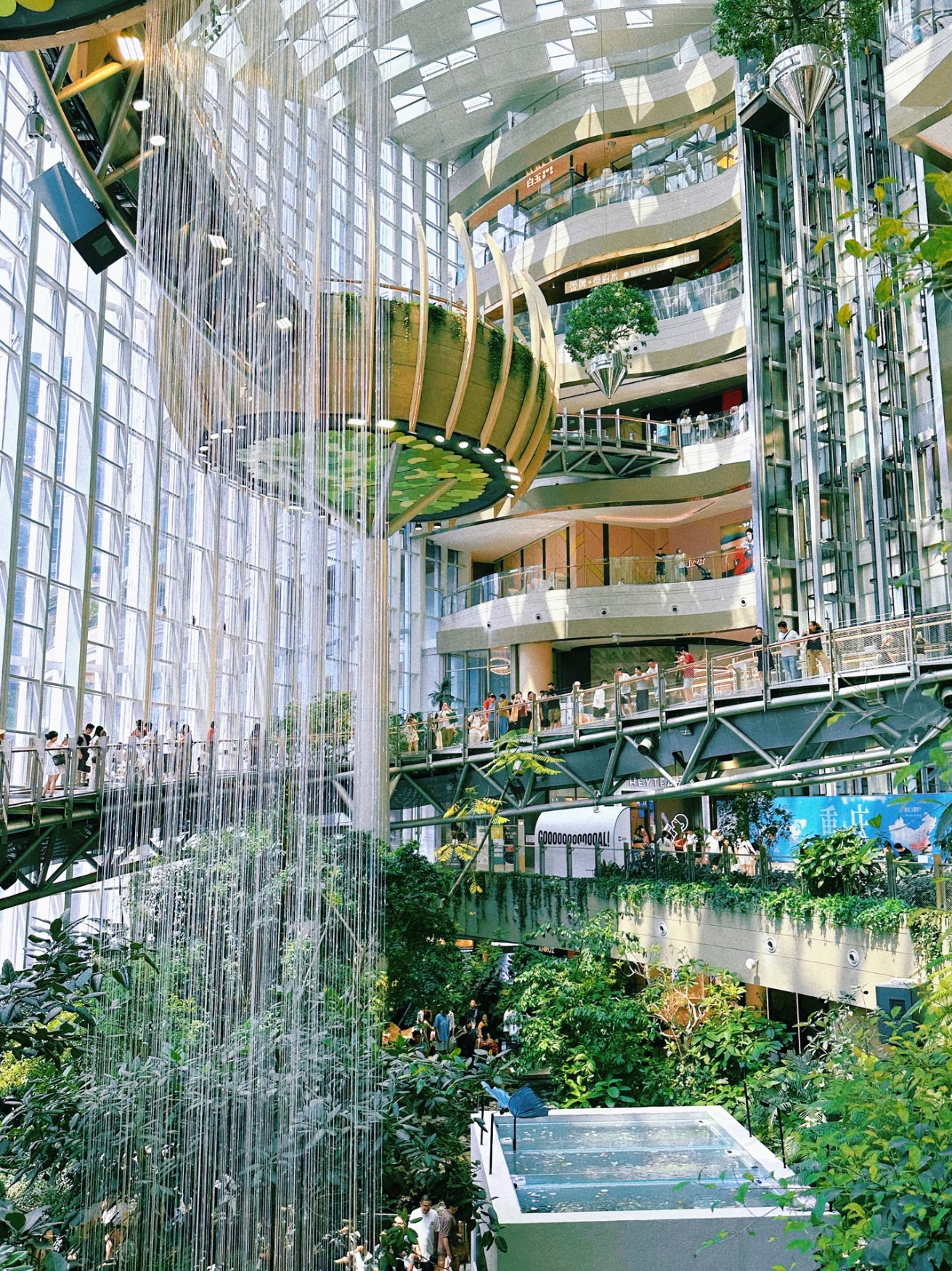It's incredibly spacious inside, featuring the Muguang Forest right in the center. It's filled with lush trees, a cascading waterfall, and fish, along with multi-level walkways to stroll around. As you wander through, you'll discover completely unique photo angles at every turn.

What I love the most is that there's no entrance fee. So, if you're visiting Chongqing and looking for an amazing spot that won't break the bank, this place is perfect.

As for getting there, taking the subway is definitely the easiest route. Just hop on Metro Line 5 and get off at Chongguang Station. You can walk straight into the mall right from the station—no need to waste extra cash on a Didi. Plus, subway fares in China are already super affordable.

I took my time exploring without any rush. Spending about 1–2 hours walking around and snapping photos feels just right. And whenever you get hungry, you can easily grab a bite to eat right inside the mall.

Also, for the photography lovers out there, I highly recommend setting aside some extra time. Once you're actually inside, there are way more photogenic spots than you might expect from pictures online—especially the view from the upper floors, where you can capture both the indoor garden and the mall all at once.

If you're traveling on a budget, checking this place out is a no-brainer:
No entrance fee
Accessible directly by Metro
No advance booking needed
Takes about 1–2 hours to explore

You can simply search for "The Ring Chongqing" or "重庆光环购物公园" on your map app.