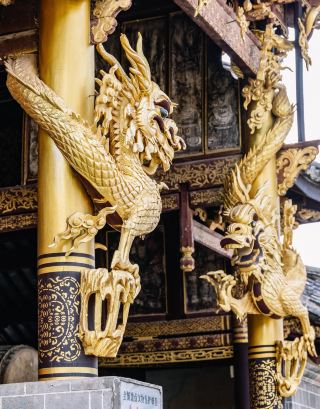 Two carved wooden golden dragons hang and coil overhead