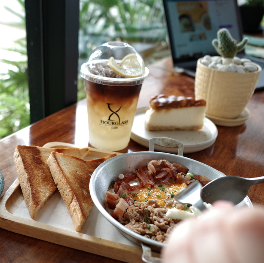 This is Hourglass Cafe, a charming cafe with a serene atmosphere located in the Thawi Watthana district. 

The cafe offers both indoor and outdoor seating areas. It serves a variety of dishes, desserts, and beverages to choose from.

This cafe is perfect for relaxing and unwinding while soaking in positive energy from the greenery. There's even a little flock of chickens roaming around the lawn, which is quite delightful to watch.