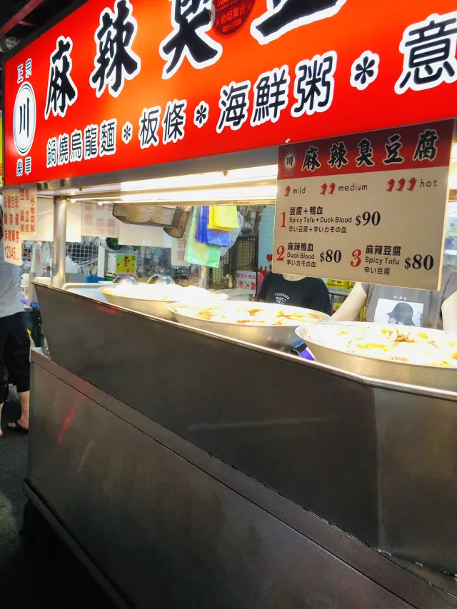 樂華夜市臭豆腐攤前的價目牌,標示豆腐加鴨血、麻辣鴨血與麻辣豆腐的價格與辣度