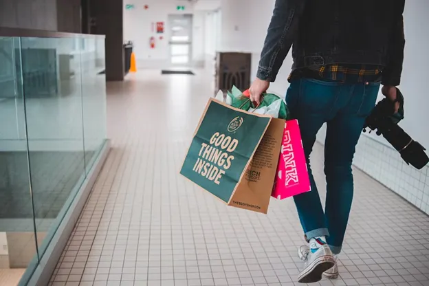 Uomo in un centro commerciale con delle borse della spesa in mano