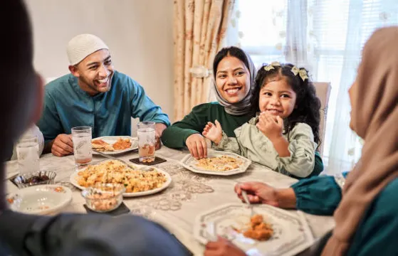Keluarga yang tersenyum menikmati hidangan bersama di rumah untuk Idul Fitri selama Ramadan