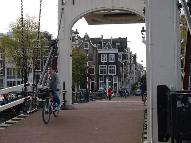 Woman biking across De Magere Brug in Amsterdam