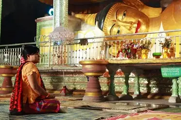  A devotee prays in front of a reclining statue of Buddha in Myanmar