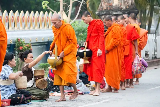 People give their offerings to roaming Buddhist monks