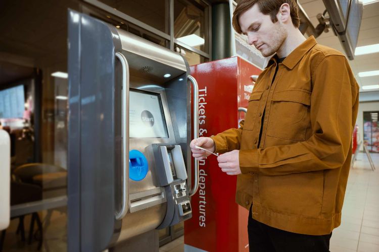 Man buying anytime train ticket at station machine.