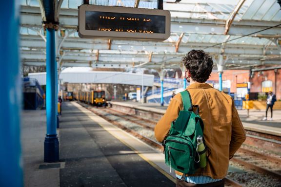 Traveler on UK train platform, Easter rail works advisory.