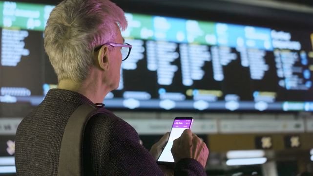 Traveler checking peak and off-peak train times on phone.