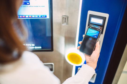 Passenger using mobile ticket at UK train barrier.