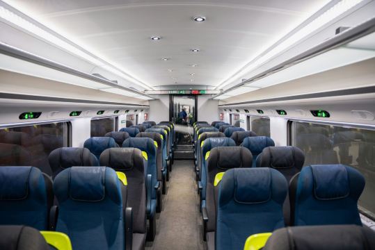 Eurostar train carriage interior with blue seats and overhead luggage racks.