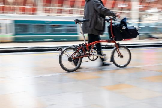 Cyclist with a folding bike at a station