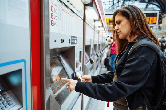 Woman booking advance train ticket at self-service machine.