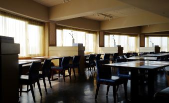 The picture displays an empty dining room featuring large windows, tables in the middle, and a set of chairs at City Suites (Taoyuan Gateway)