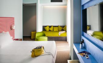 a modern hotel room with a bed , couch , and tv , along with green pillows and a white comforter at Glam Milano