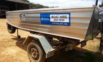 a boat with a trailer attached to it is parked in a field , and a sign on the back at Nutkin Lodge