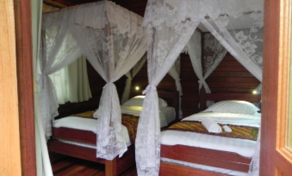 a room with two beds , one on top of the other , covered with white mosquito nets at Borneo Natural Sukau Bilit Resort