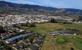 a bird 's eye view of a city with buildings , green spaces , and mountains in the background at Greens Motel