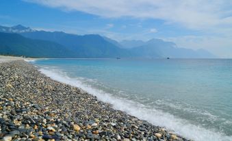 a beautiful beach with clear blue water , white sand , and rocks , as well as mountains in the background at Ocean Hotel