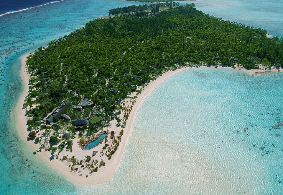 a tropical island with a white sandy beach and clear blue water , surrounded by lush green vegetation at The Brando