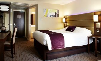 a large bed with a purple blanket and white sheets is in a hotel room at Premier Inn Glasgow (Bearsden)