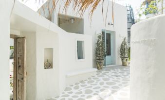 a white house with a tiled floor and a small window , surrounded by palm trees at Resort de Paskani