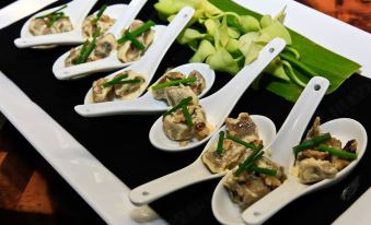 a table with a black tablecloth has several white spoons filled with food and garnished with green onions at Quest Liverpool