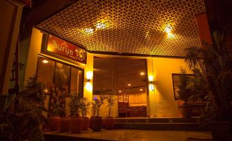 a restaurant with a red sign and yellow walls , surrounded by potted plants and a dining area at Hotel Sangam