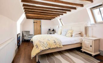 a large bed with a wooden headboard is situated in a bedroom with slanted ceiling at The Lamb at Angmering