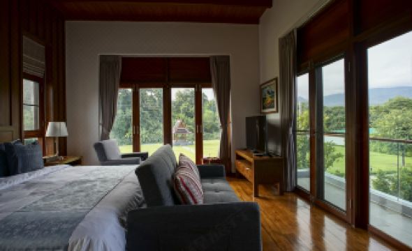 a spacious bedroom with a large bed , a couch , and a tv . the room has hardwood floors and has a view of at Mae Rim Grace