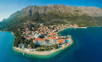 an aerial view of a small town surrounded by water , with a mountain in the background at Tui Blue Makarska - Adults Only