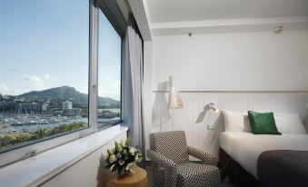 a hotel room with a large window overlooking a beautiful view , featuring a bed , a chair , and a table at The Ville Resort - Casino
