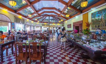 The restaurant is adorned with a red floral pattern on the ceiling and features spacious tables and chairs at Ta Prohm Hotel & Spa