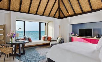 a luxurious bedroom with a large window overlooking the ocean , creating a serene and inviting atmosphere at Four Seasons Resort Maldives at Kuda Huraa