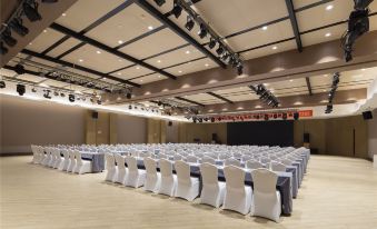 a large conference room with rows of chairs arranged in a semicircle , and a podium at the front at M Hotel