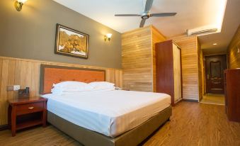 a large bed with a wooden headboard is in a room with a ceiling fan and a painting on the wall at Summer Bay Resort, Lang Tengah Island