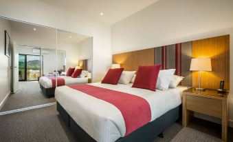 a large bed with a red blanket and white sheets is in a hotel room at Quest Wodonga
