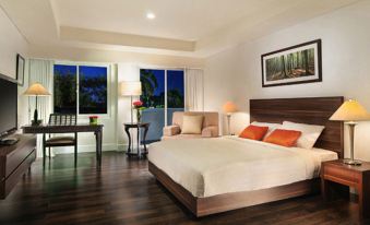 a well - lit hotel room with a large bed , two chairs , and a window overlooking the ocean at Delonix Hotel Karawang
