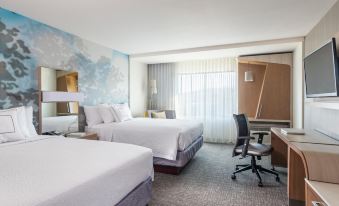 a modern hotel room with two beds , a desk , and a window , all decorated in white and blue colors at Courtyard Lake Jackson