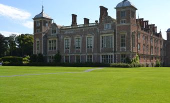 a large brick building surrounded by a lush green lawn , creating a picturesque setting for a formal setting at Brasteds