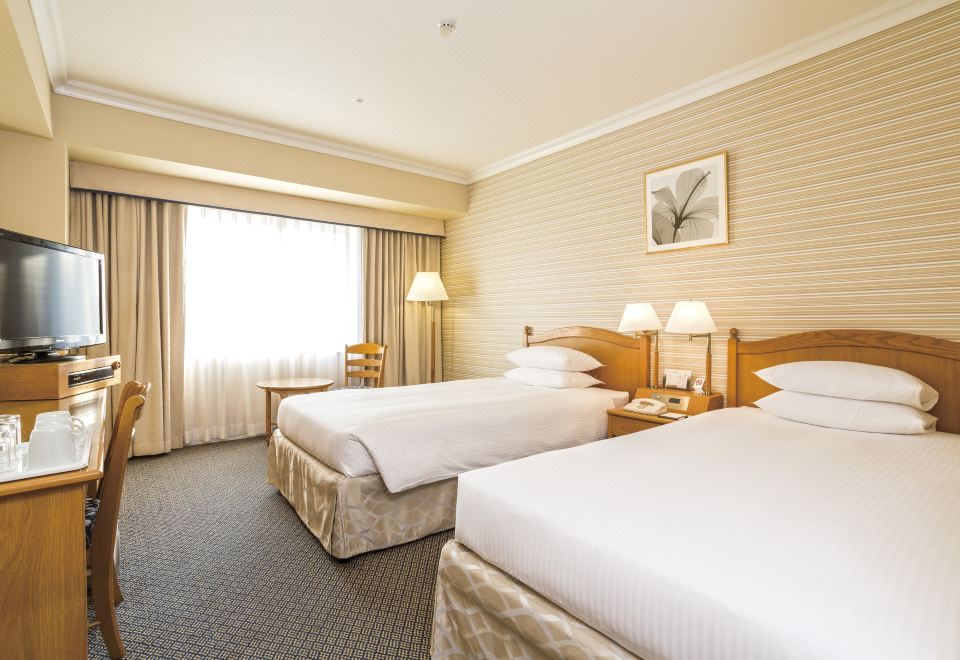 a hotel room with two beds , one on the left side and the other on the right side of the room at Oriental Hotel Tokyo Bay