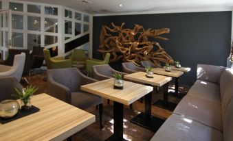 a modern restaurant with wooden tables and chairs , a large sculpture on the wall , and gray seating at Falkensee