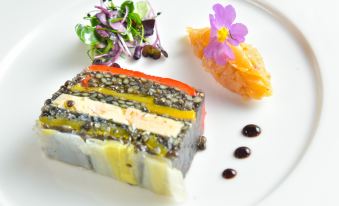 a white plate with a slice of cake and a side of vegetables , accompanied by a flower at Hotel Golf Chateau de Chailly