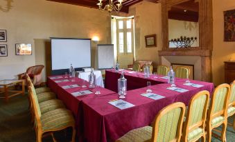 a conference room with a long table covered in red tablecloth , several chairs , and bottles of water on the table at Hotel Golf Chateau de Chailly