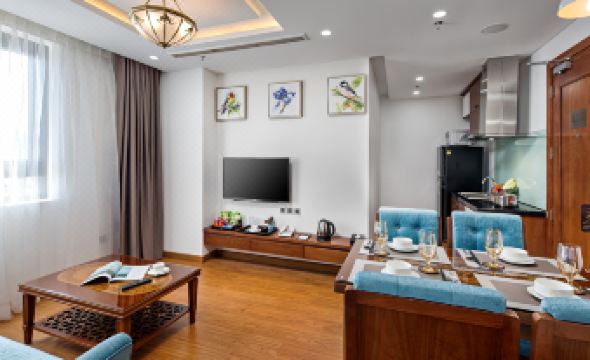 a modern living room with a wooden floor , blue and white chairs , a flat - screen tv , and a coffee table at Paris Deli Danang Beach Hotel