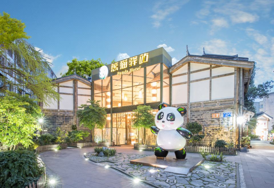 a large panda statue stands in front of a building with chinese characters on it at Panda Hotel
