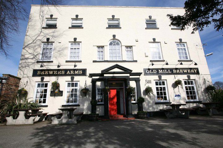 "a large , white building with a sign that reads "" brewers arms "" and "" old mill brewpub .""." at The Brewers Arms