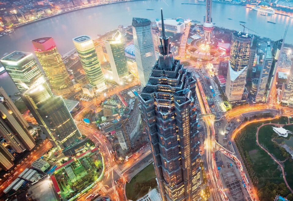 At night, a city's skyline and skyscrapers are illuminated in blue hues at Grand Hyatt Shanghai