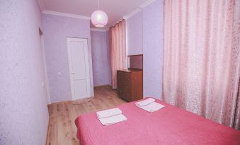 a room with a pink bed , purple curtains , and a wooden floor , as well as a tv and dresser at Veranda
