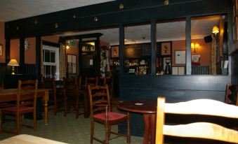 a dimly lit restaurant with several tables and chairs , as well as a bar area at The Foxham
