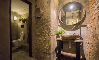 a bathroom with stone walls and a wooden vanity , featuring a large mirror above the sink at Z Hotel